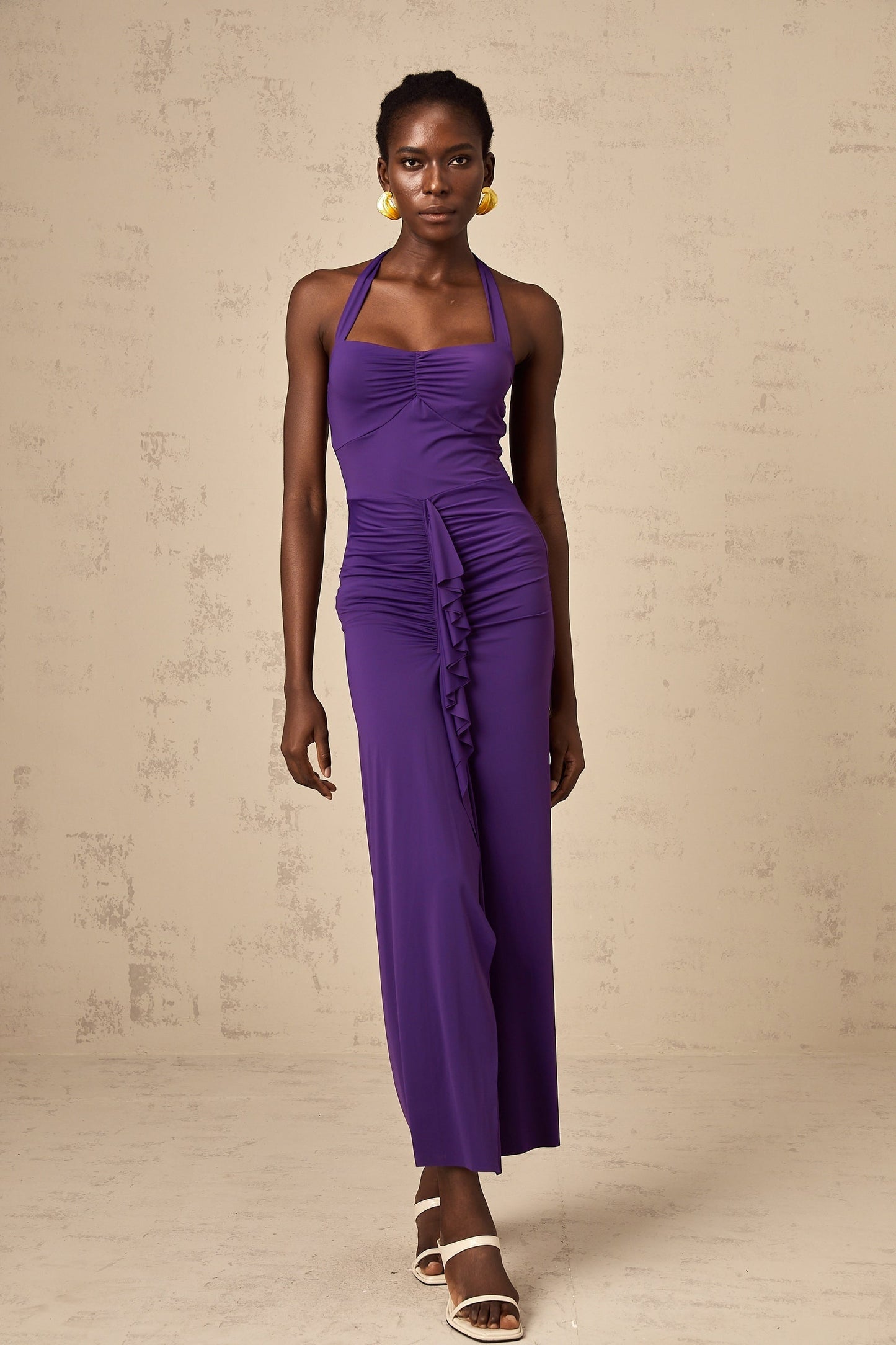 A purple halterneck midi dress with ruched detailing on a female model