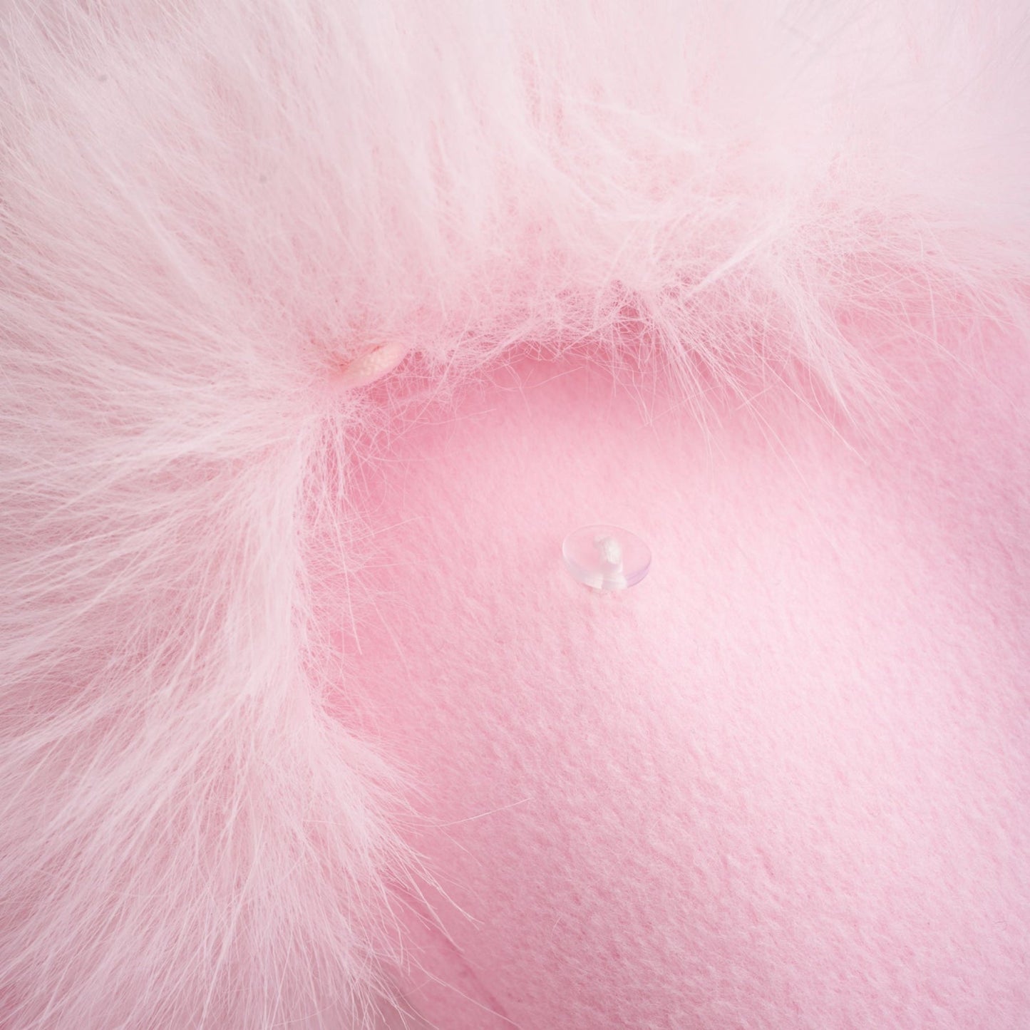 A pink oversized coat made of faux fur with a plush texture and long sleeves