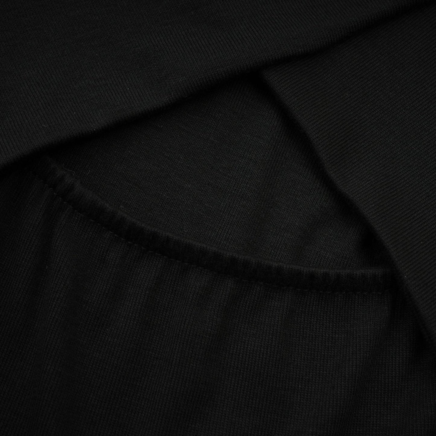 A black ruched top with long sleeves made of stretchy jersey fabric called Odette