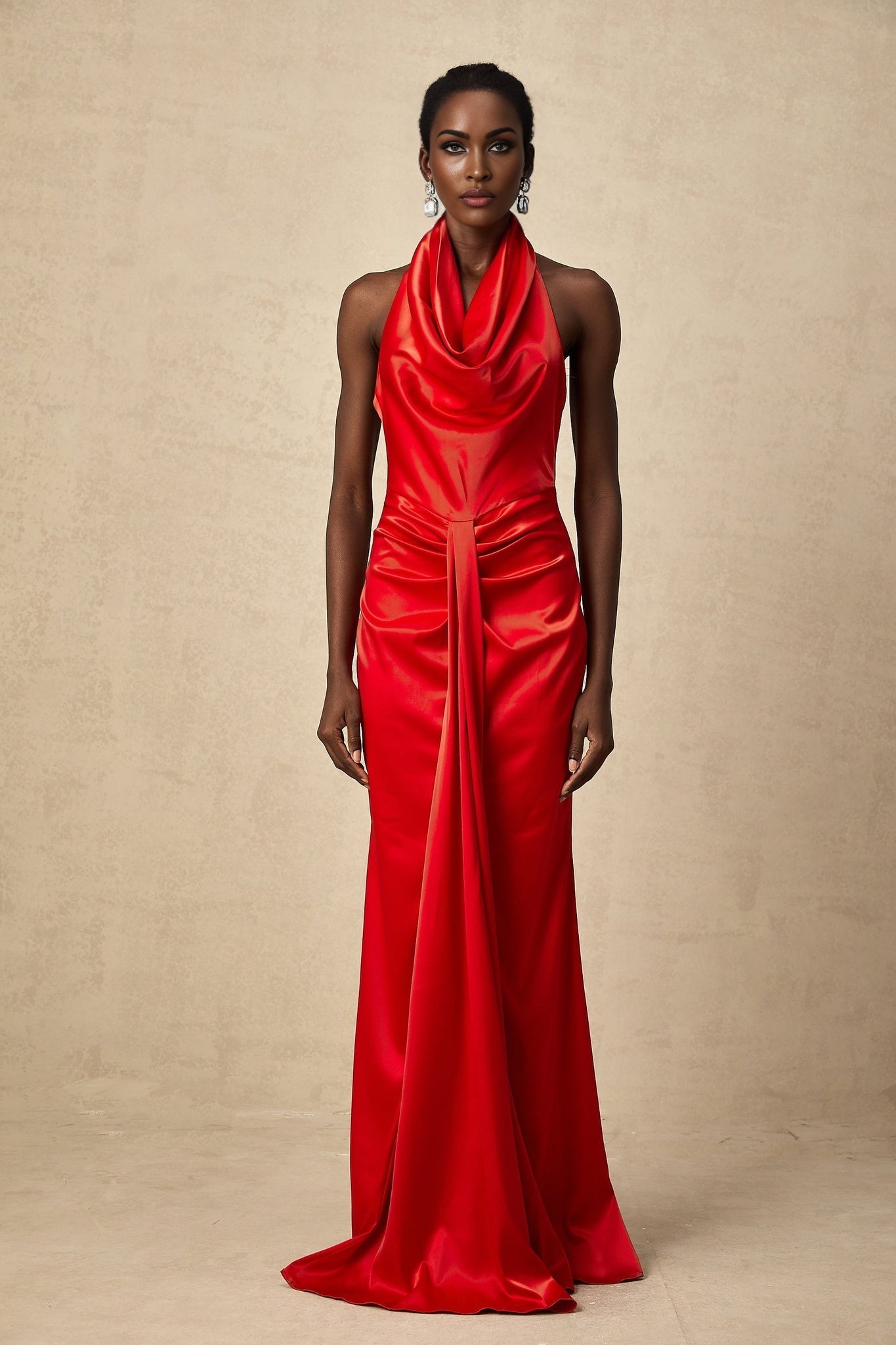 Woman wearing a long red satin maxi dress with halter neckline and draped design