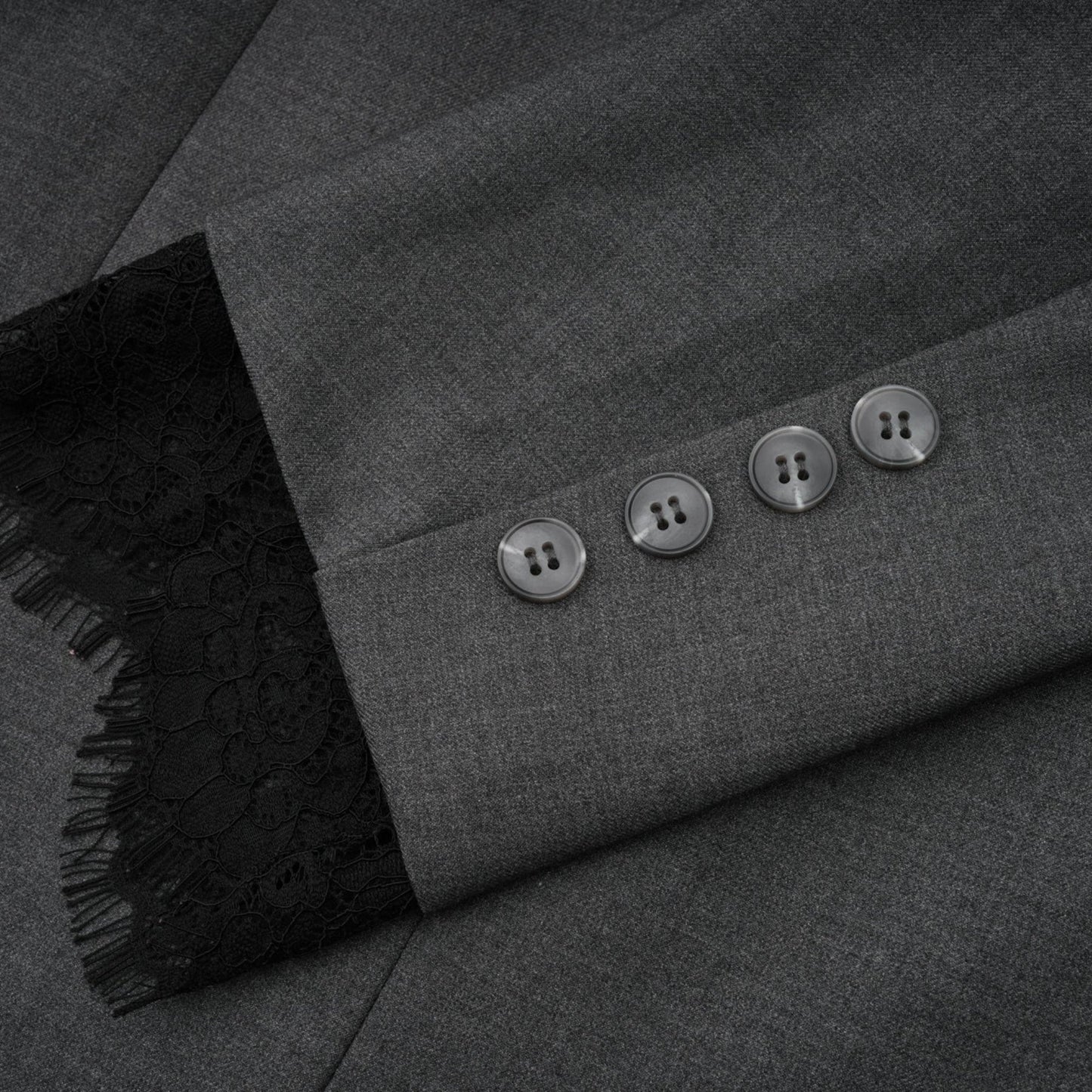 Woman wearing grey blazer with lace panel detailing on sleeves and back