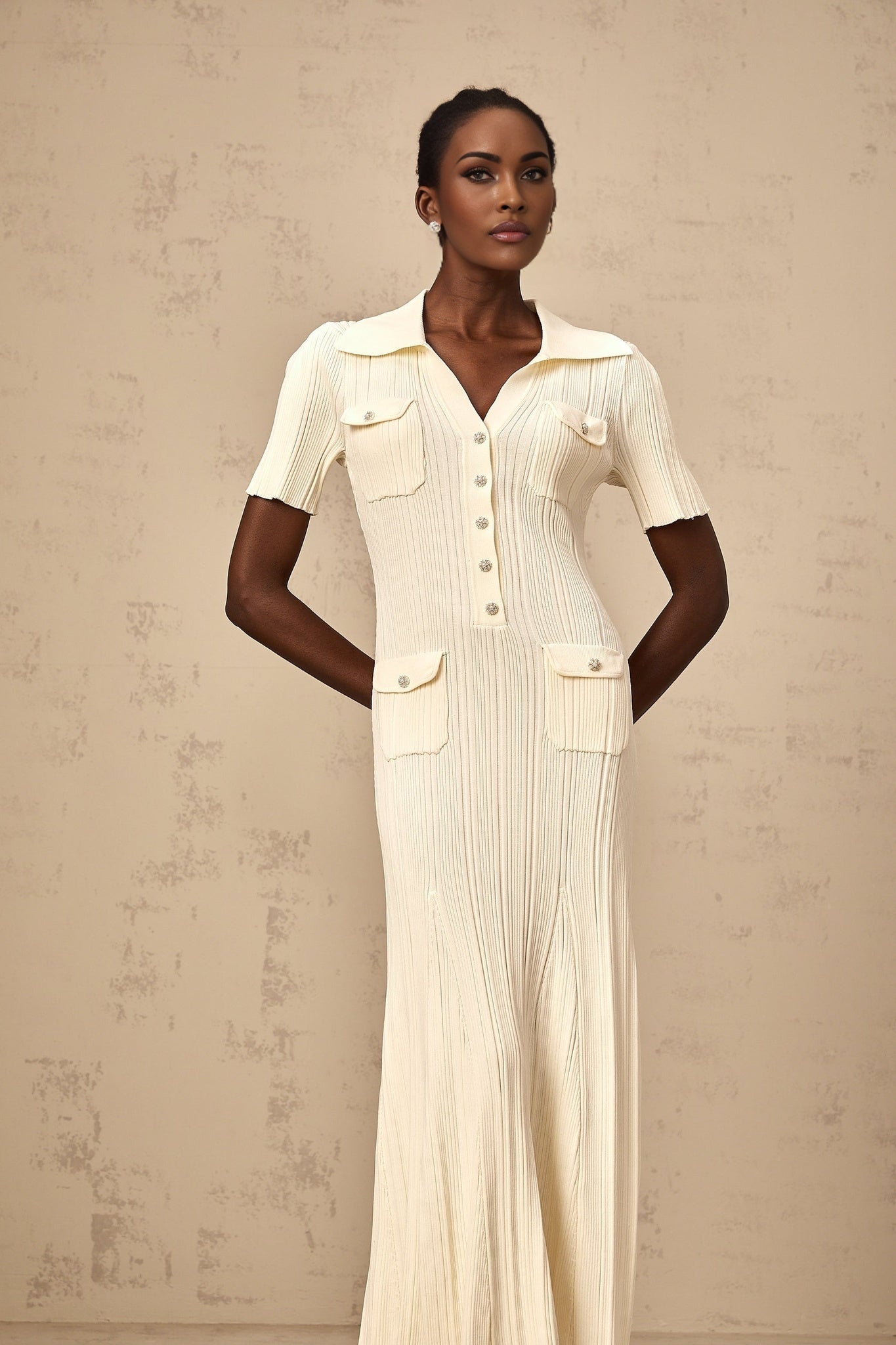 A woman wearing a beige ribbedknit midi dress with long sleeves and a formfitting silhouette standing in a neutral background