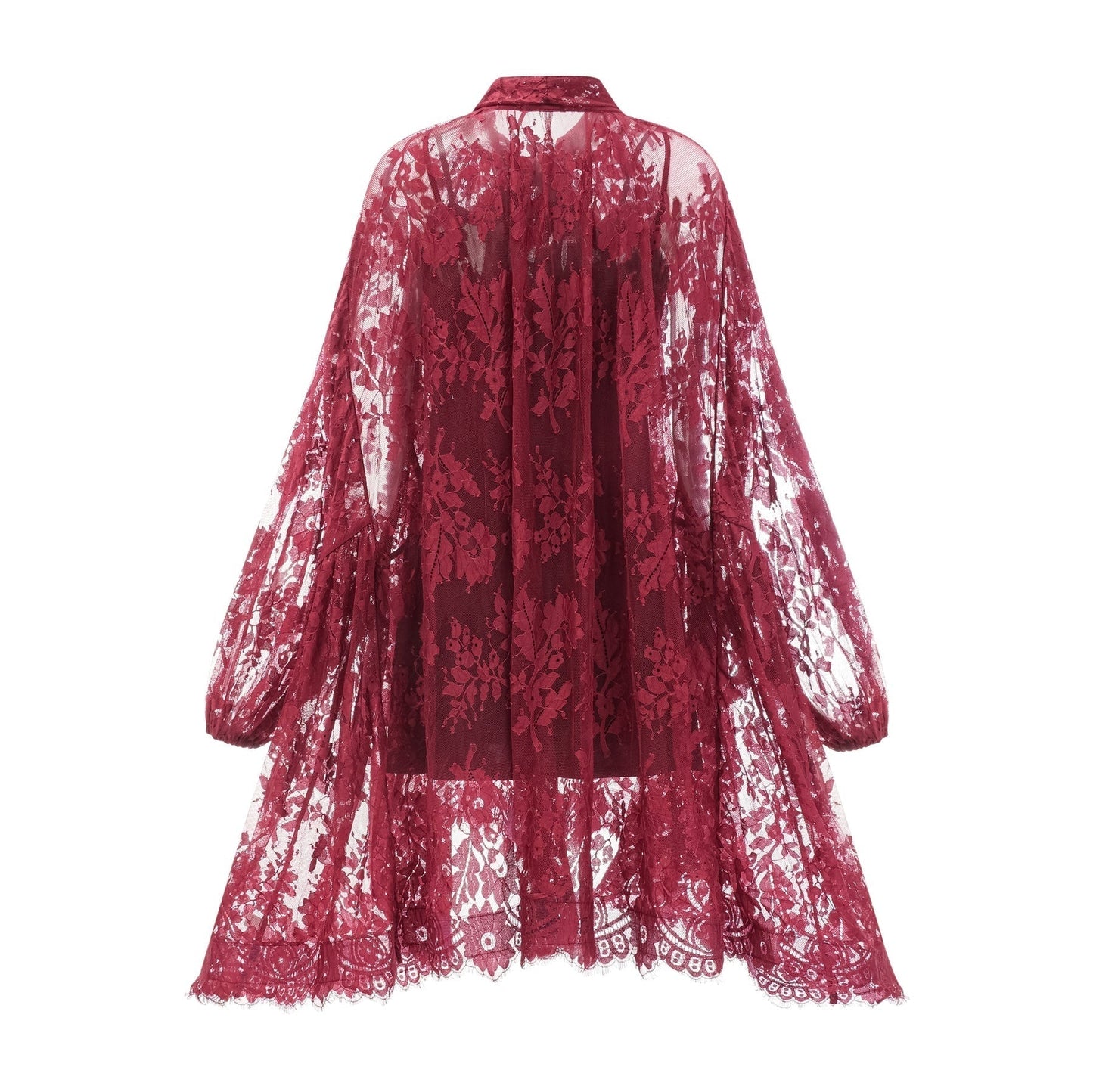 A woman wearing a flowing red lace dress with an oversized fit standing against a plain background