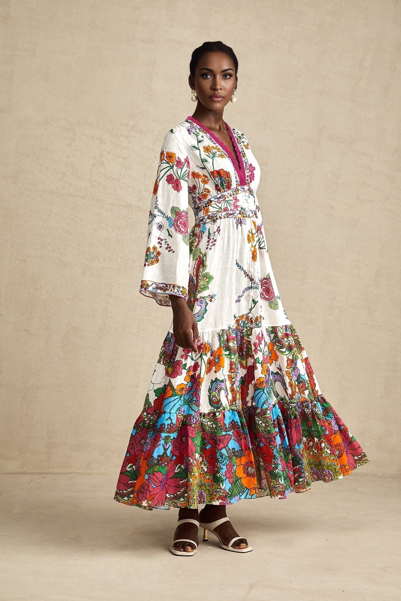 A woman wearing a floral print midi dress with a V neckline and long sleeves standing in a relaxed pose