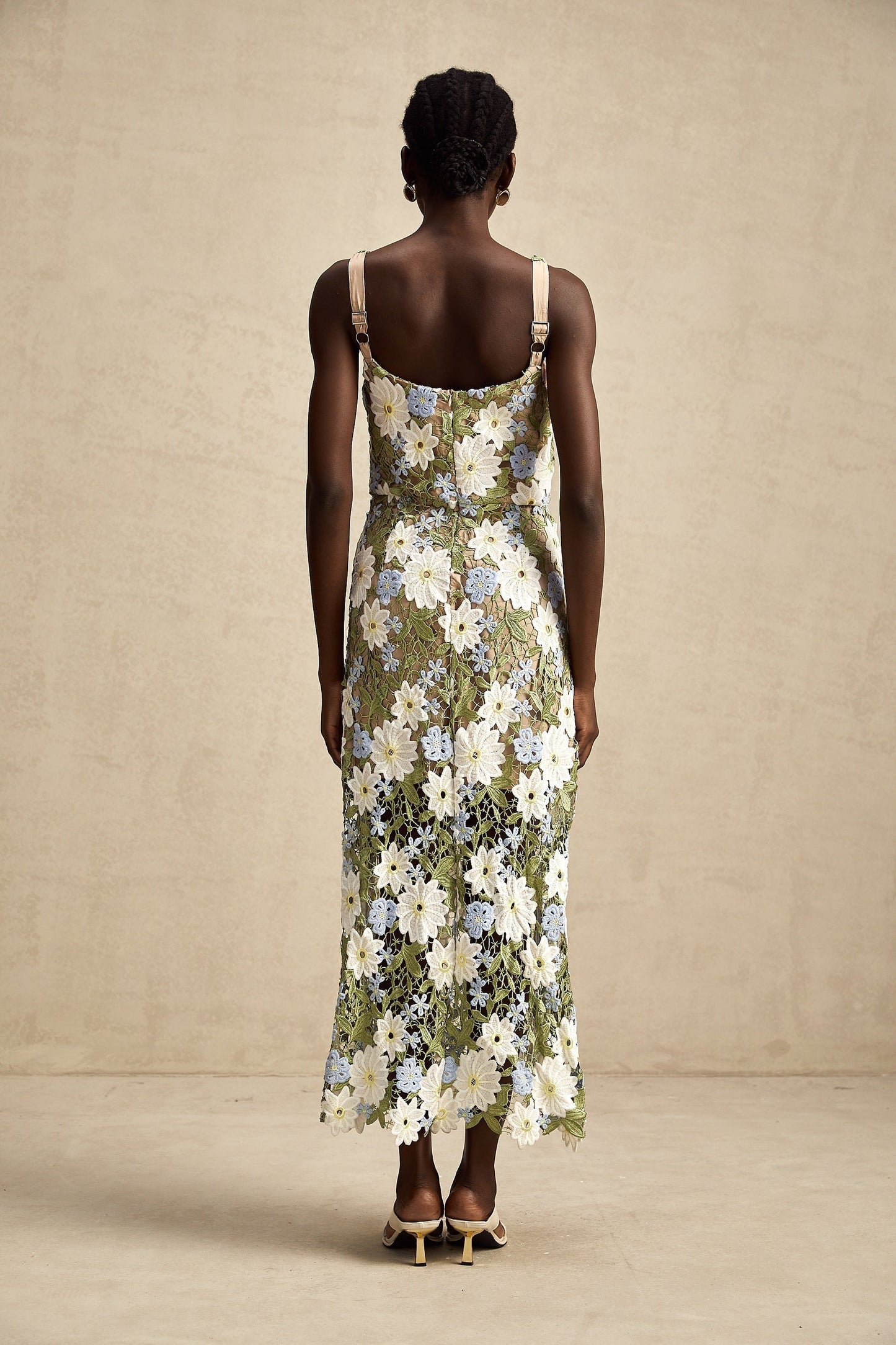 Woman wearing a white midi dress with floral embroidery and cutout details