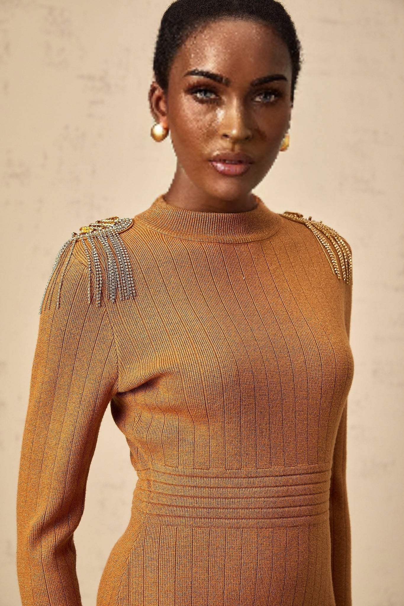 A woman wearing a ribbed knit midi dress with epaulet details on the shoulders The dress has a fitted silhouette and falls to mid calf length