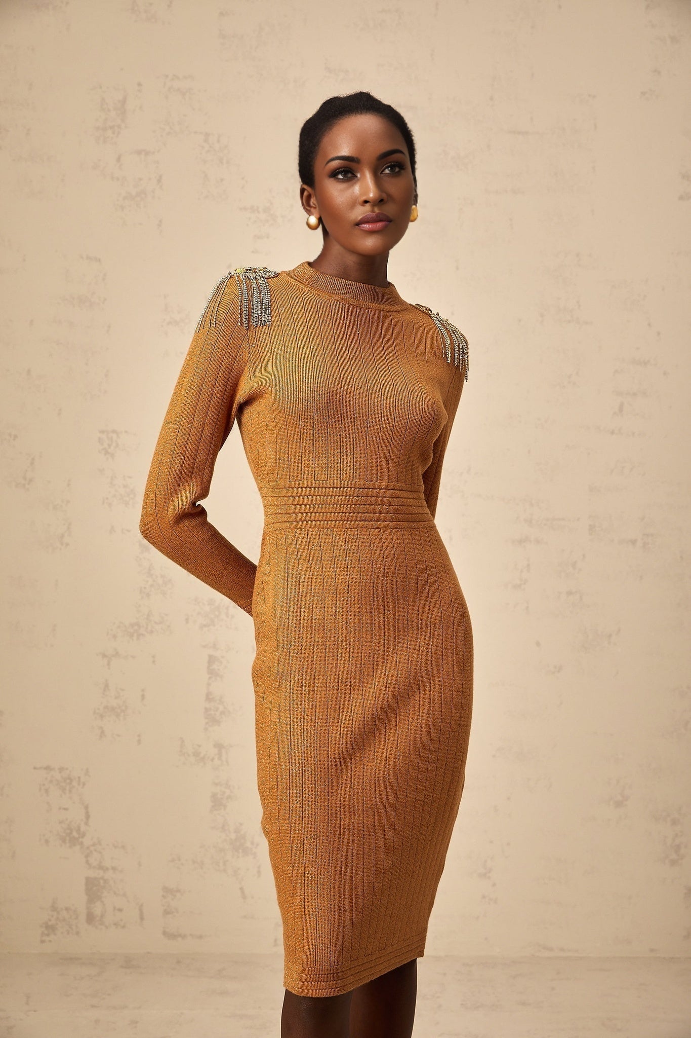 A woman wearing a ribbed knit midi dress with epaulet details on the shoulders the dress has a fitted silhouette and falls to mid calf length