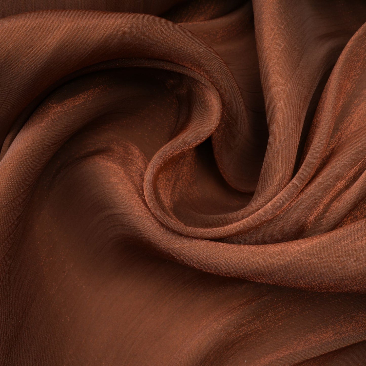 Woman wearing long brown satin dress with pleated details and flowing maxi skirt