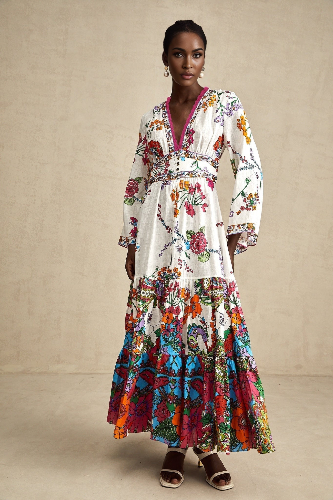 Woman wearing floral print midi dress with Vneck in soft colors standing against plain background