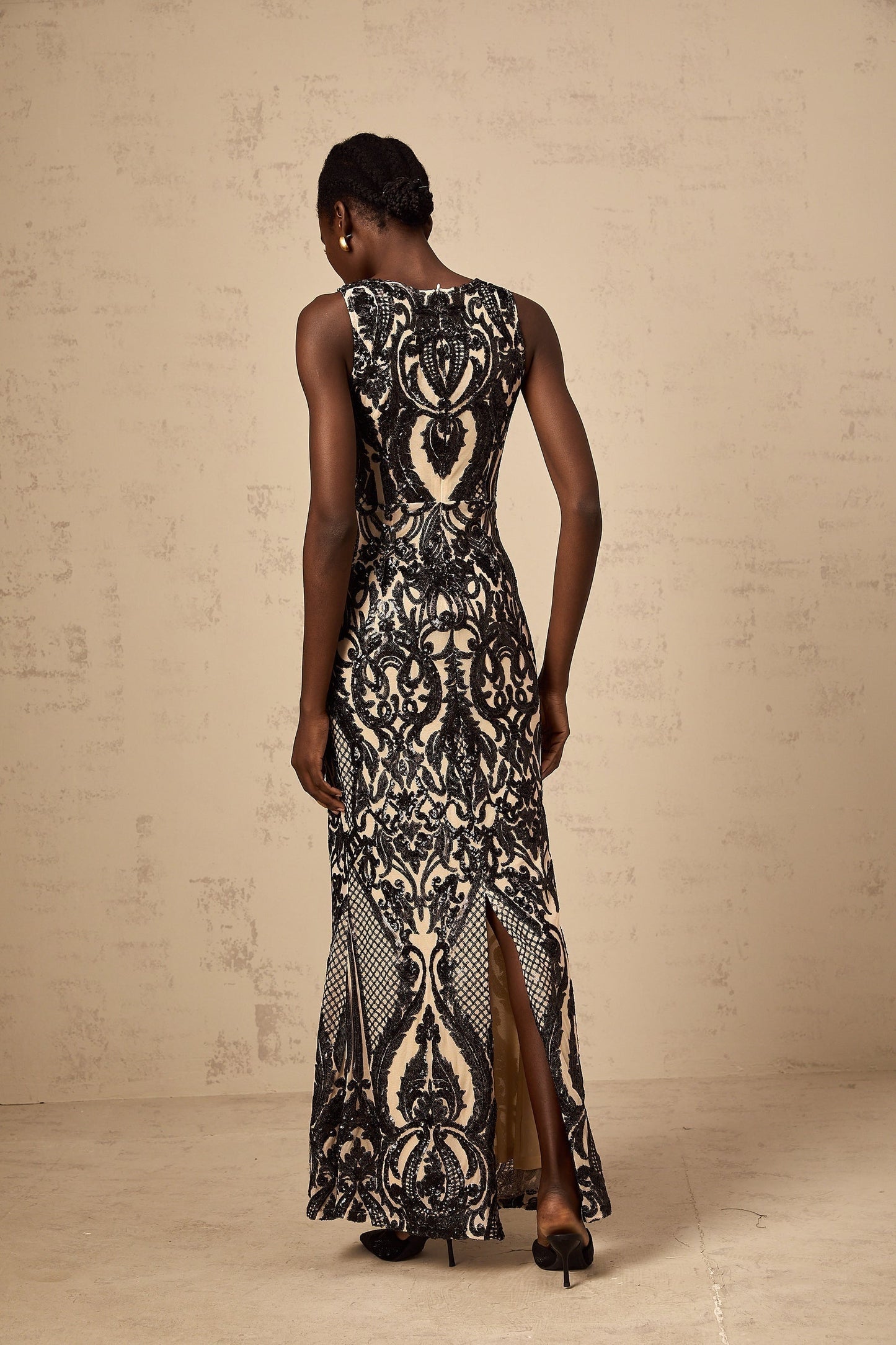A long flowing maxi dress with sheer mesh fabric adorned with sparkly sequins creating an elegant and glamorous look