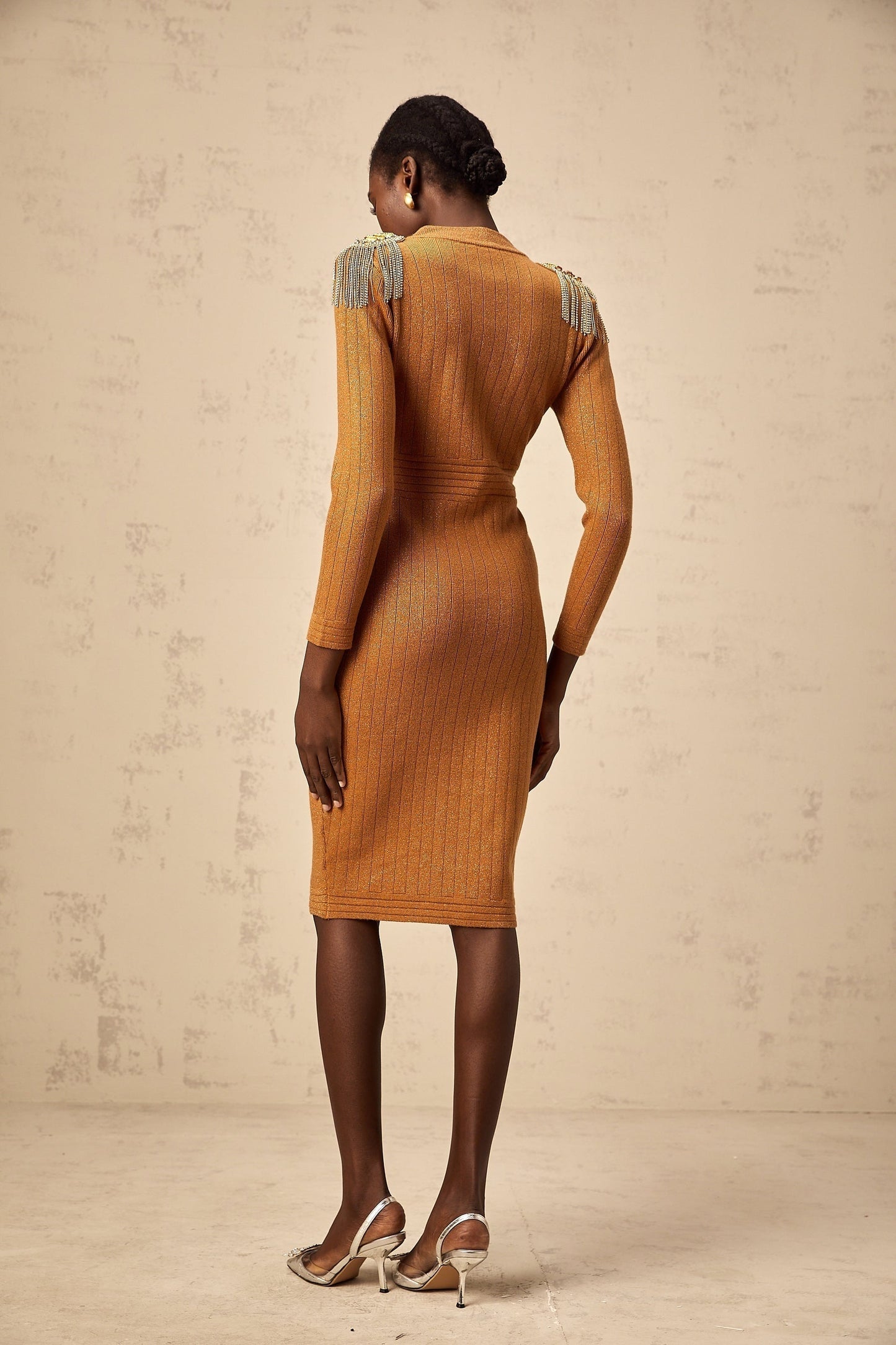 Woman wearing a navy blue ribbed knit midi dress with epaulet details on the shoulders fitted silhouette and long sleeves