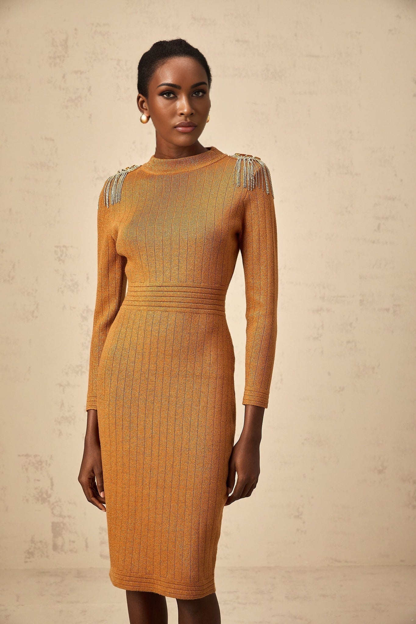 A woman wearing a ribbed knit midi dress with epaulet details on the shoulders The dress is form fitting and extends to mid calf length showcasing a classic silhouette