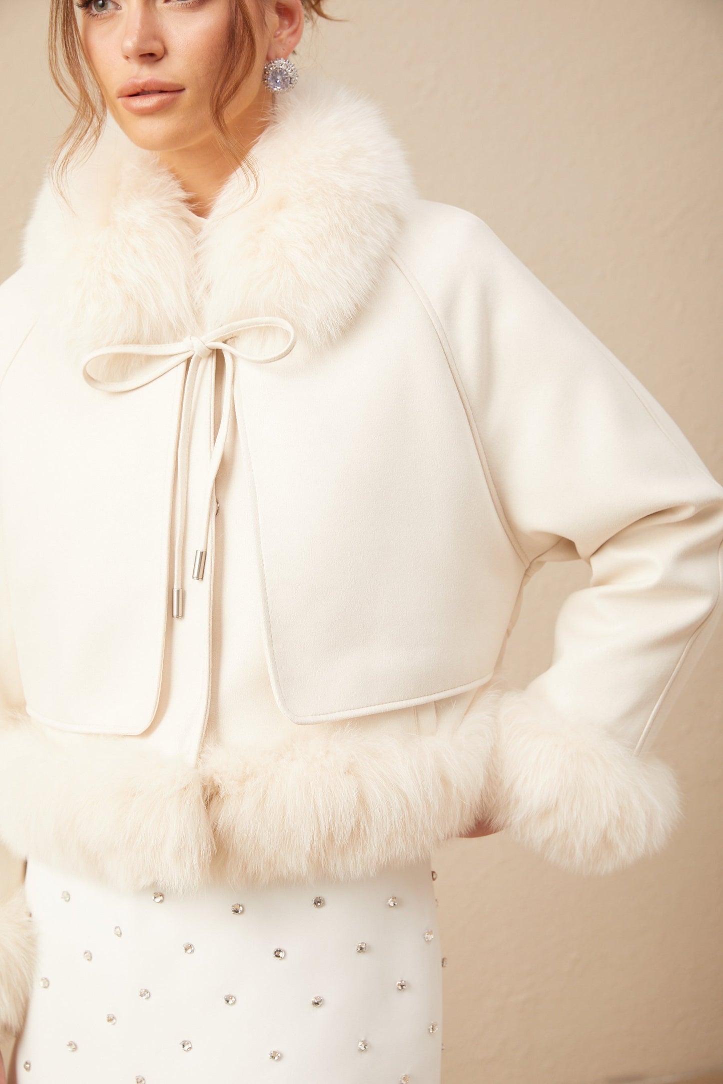 Woman wearing white short suede coat with fur trim and padded design