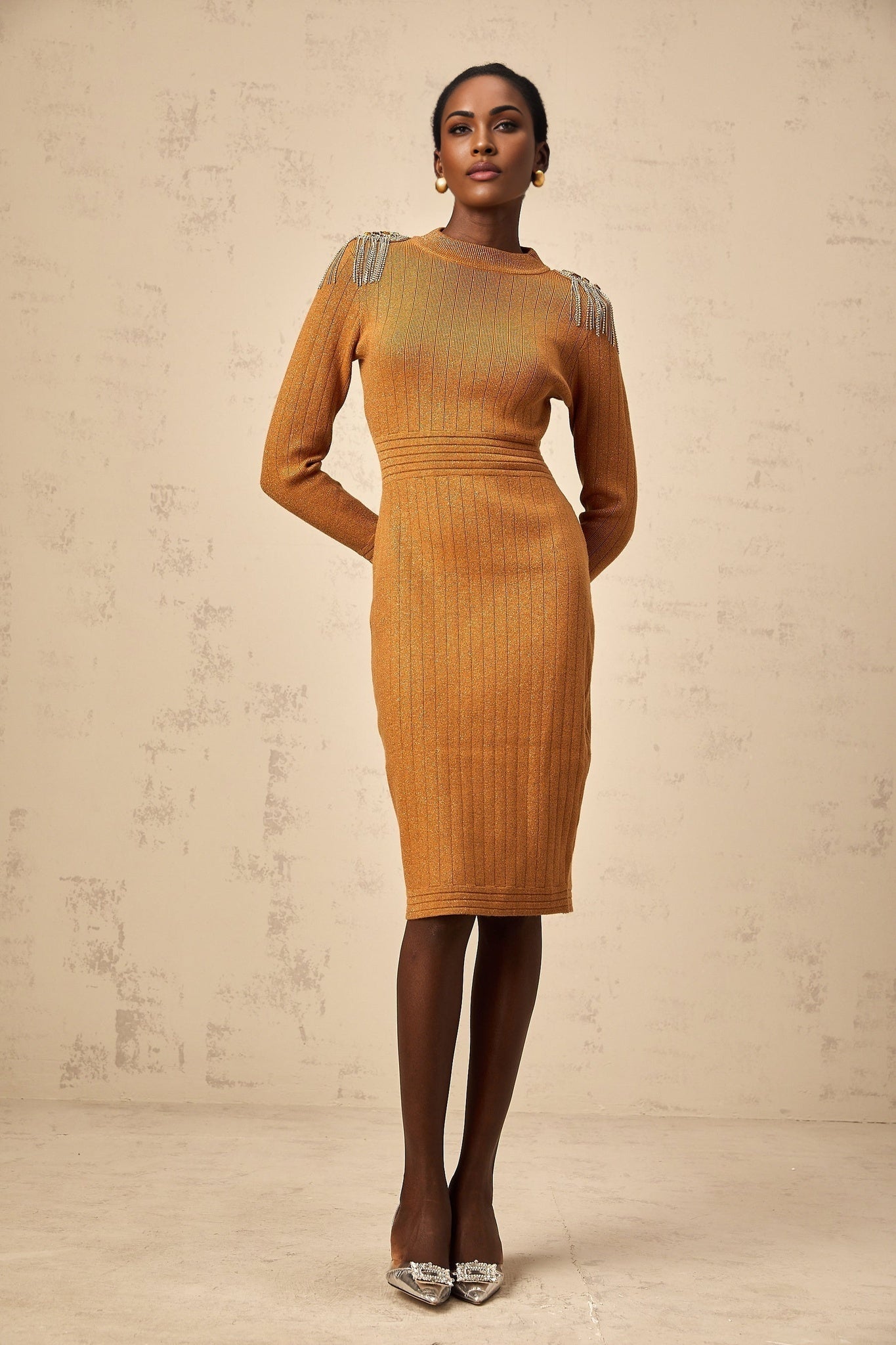 Woman wearing a ribbed knit midi dress with epaulet details on the shoulders in a neutral color