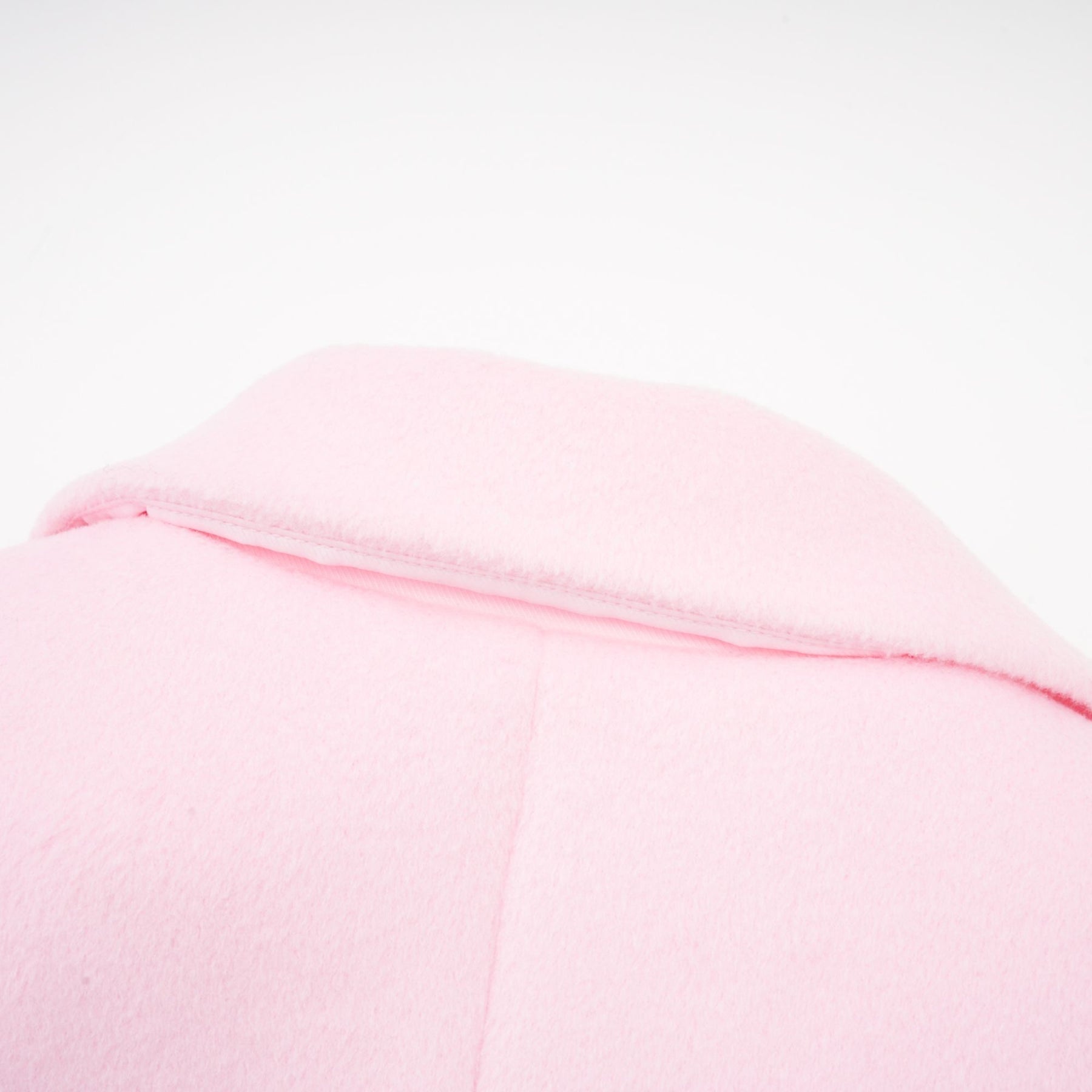 A pink overcoat made of faux fur called Louisette hanging on a clothing rack