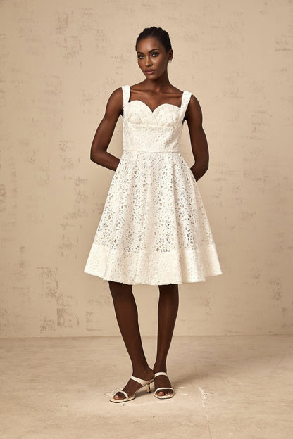 Woman wearing a white midi dress with floral lace pattern and sleeveless design