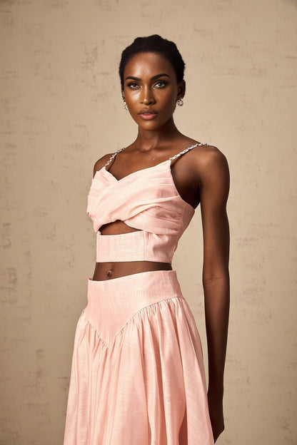 A woman wearing a pink matching set consisting of an asymmetric ruffled top and skirt The top features a oneshoulder design with ruffles while the skirt has a fitted silhouette Both pieces are in a vibrant pink color