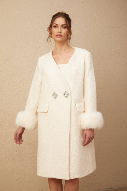 Woman wearing a white collarless textured fur coat standing against a plain background
