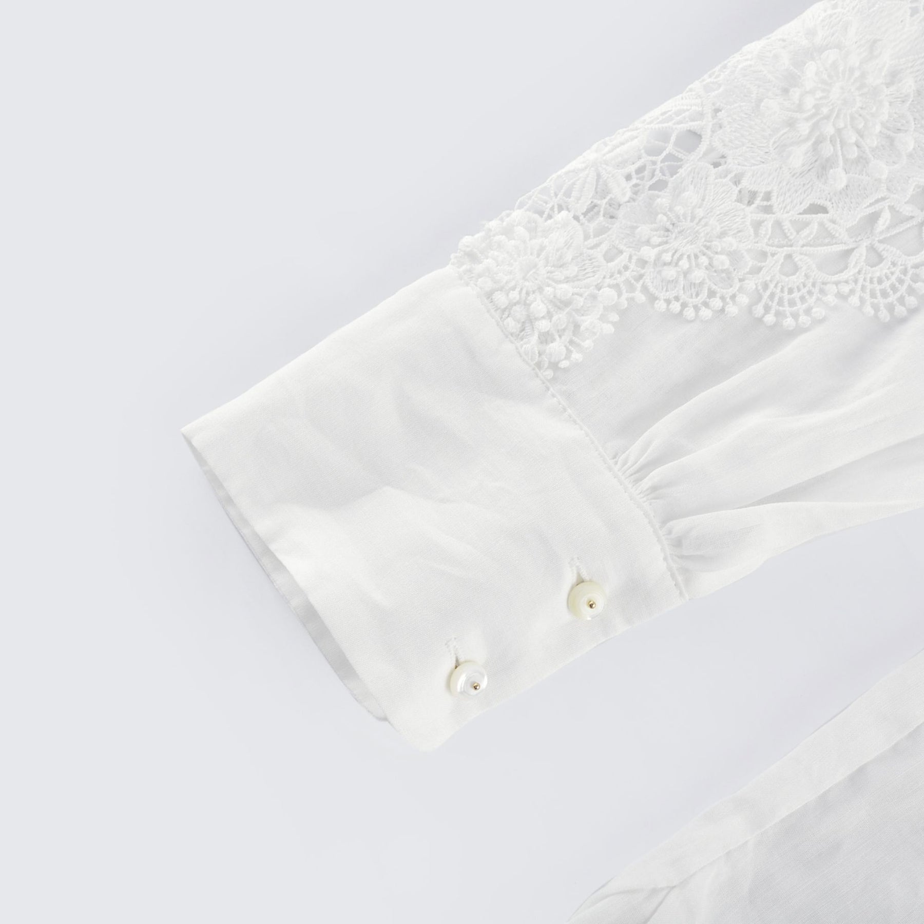 White blouse with lace embroidery and cut out details on the shoulders and sleeves