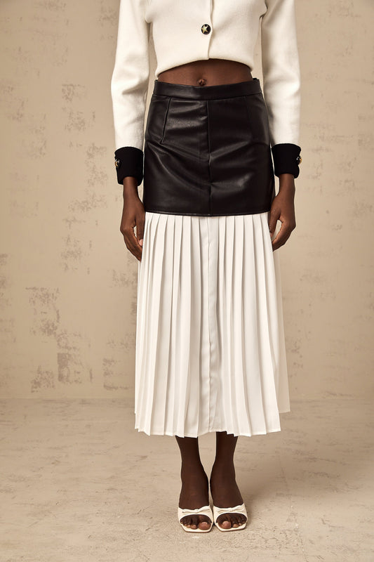 Woman wearing a colorblocked pleated midi skirt with contrasting panels in multiple colors standing in a neutral background