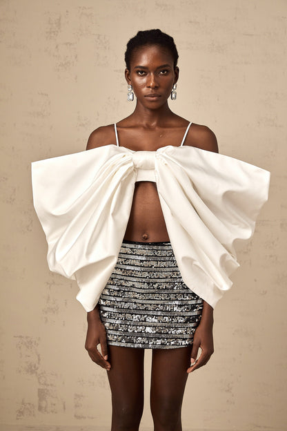 A white sleeveless top with a scoop back and decorative bowknot detail