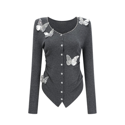 Woman wearing a grey cardigan with sequined butterfly designs on the front and sleeves