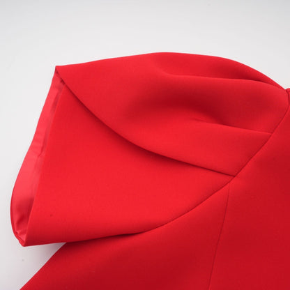 Young woman wearing a short red dress with petal sleeves and a cutout detail featuring a bow