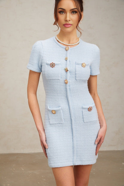 Woman wearing short blue knit dress with crystal embellishments