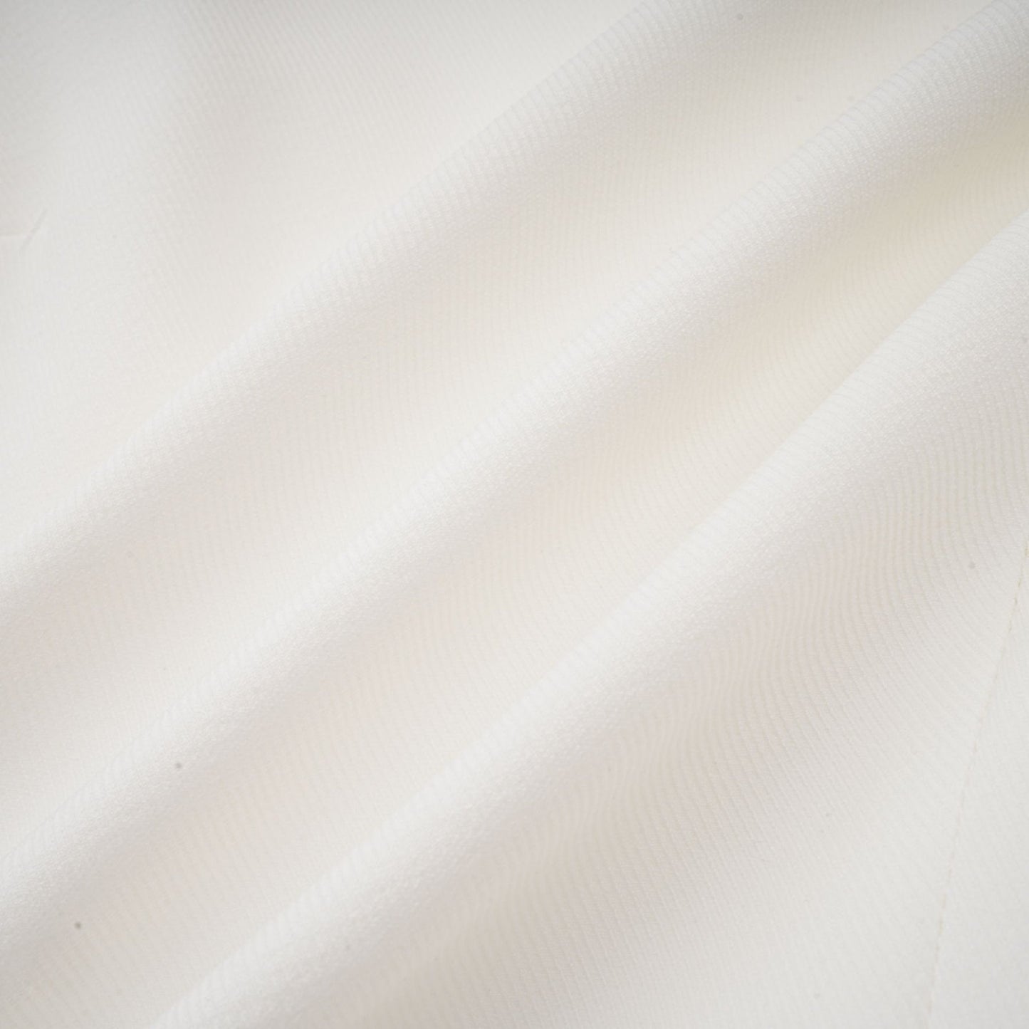Young woman wearing a white mini dress with a bubble skirt and short sleeves standing against a plain background