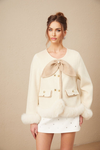 Woman wearing a short coat with contrasting colors and large bow detail at the waist