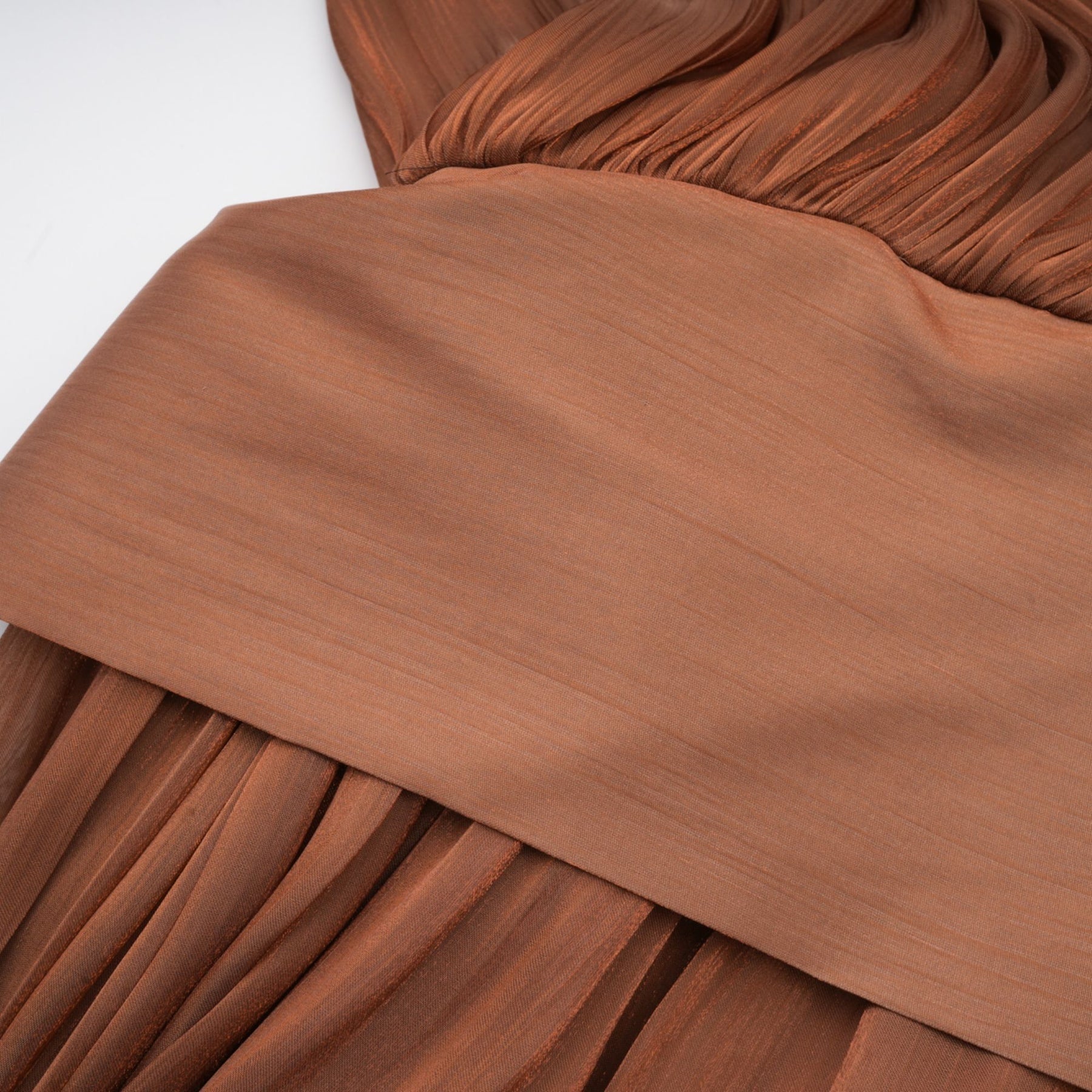 Woman wearing long brown pleated satin maxi dress with flowy skirt and fitted bodice