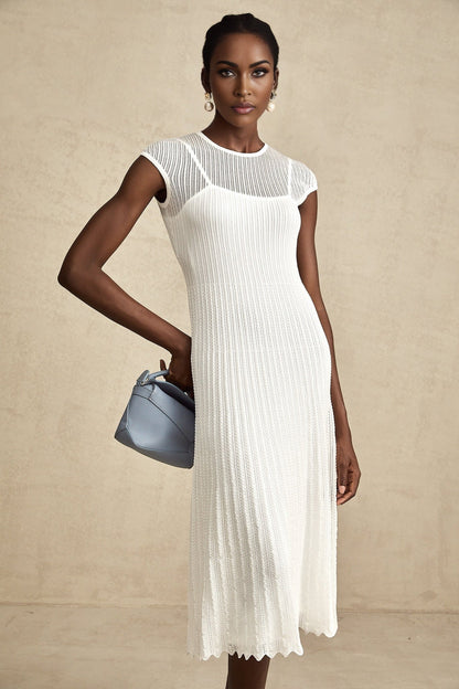 A white midi dress with scalloped hem and semi sheer fabric featuring a sleeveless design and fitted silhouette