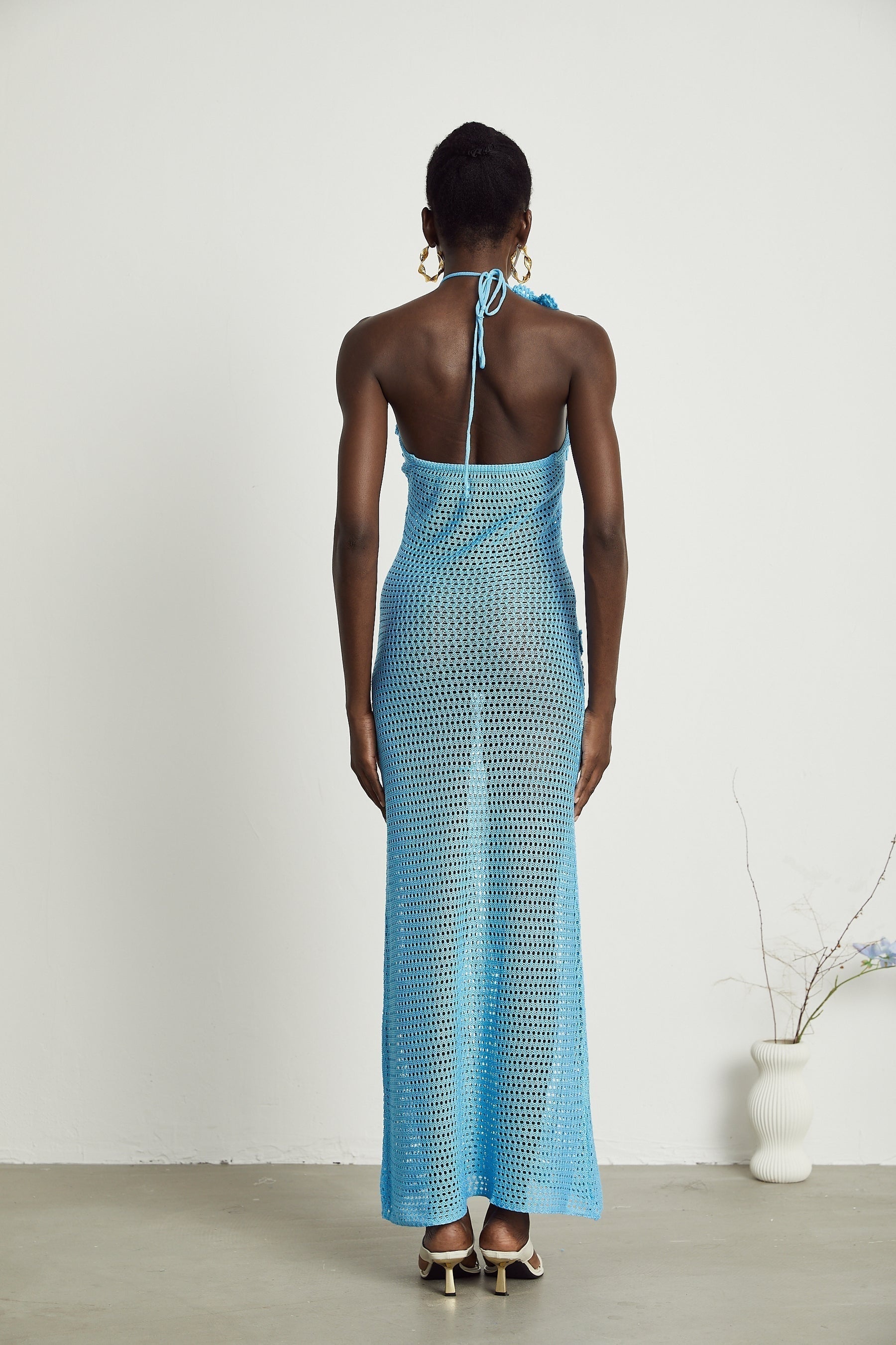 A long white crochet maxi dress with colorful faux flower embellishments scattered throughout the design