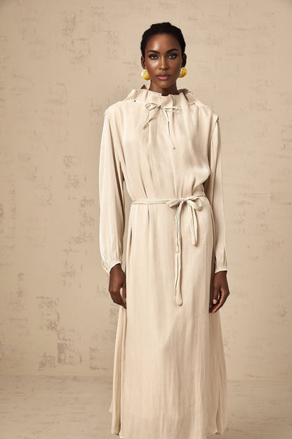 A woman wearing a lightcolored tulle midi dress with a selftie waist standing in a relaxed pose