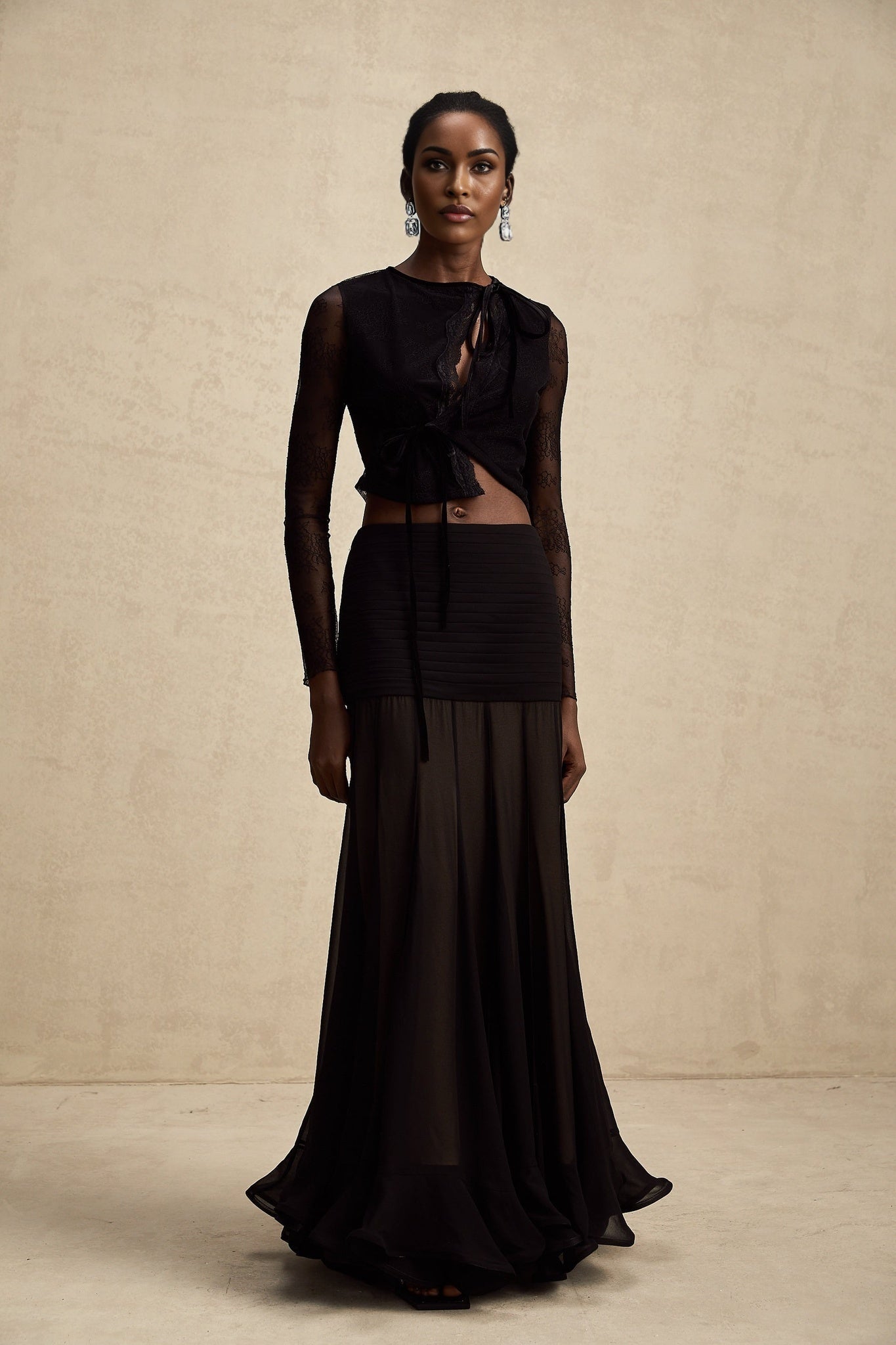 A black cropped top with sheer lace trim and see through details worn by a model