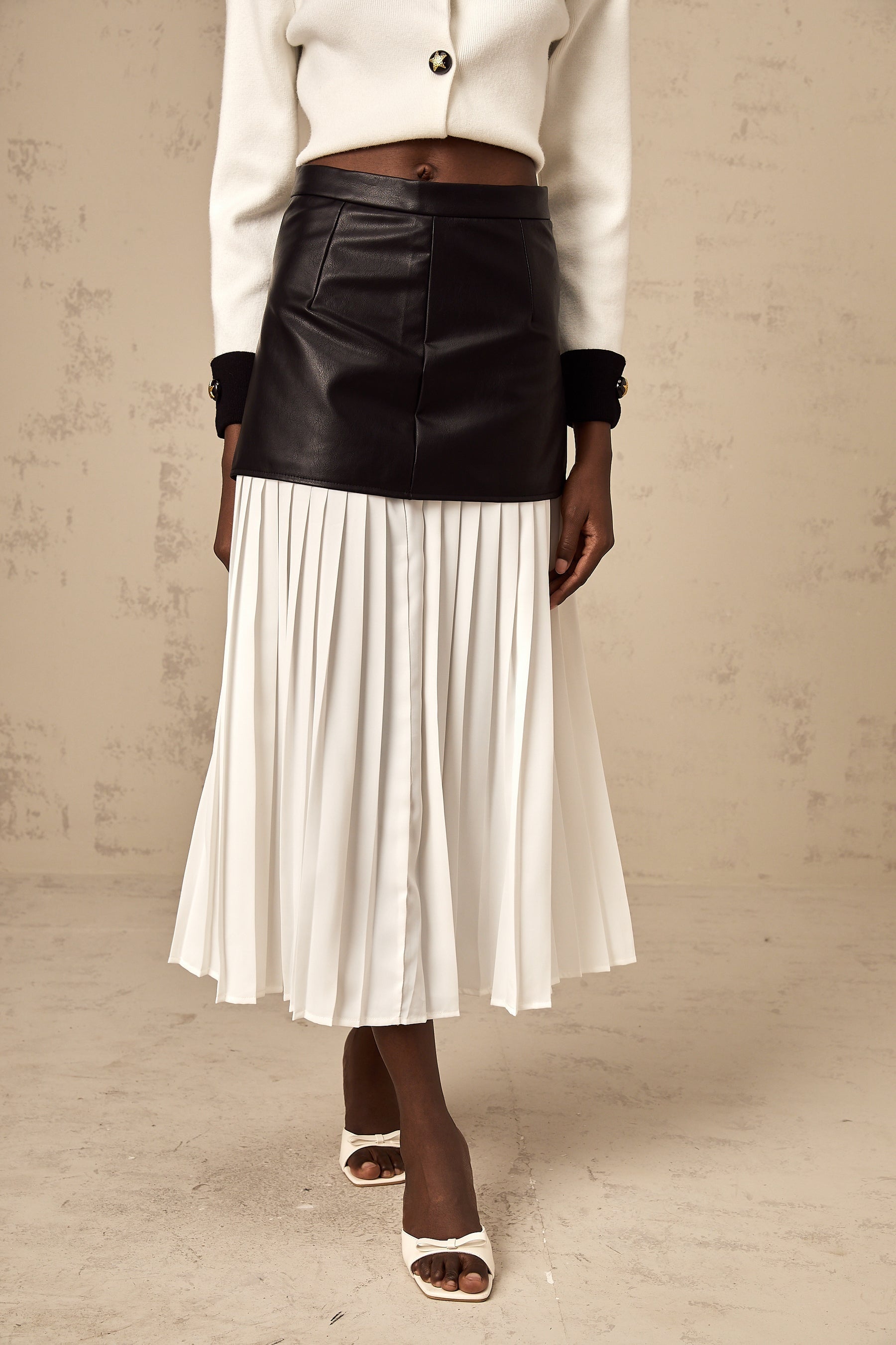 Woman wearing a midi length pleated skirt with color blocked panels in contrasting shades