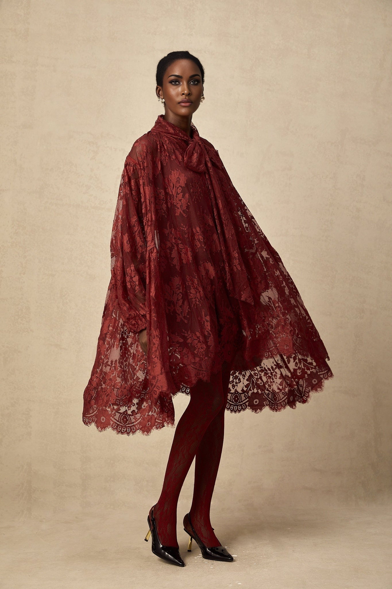 Woman wearing a long red lace dress with loose fit and sheer details