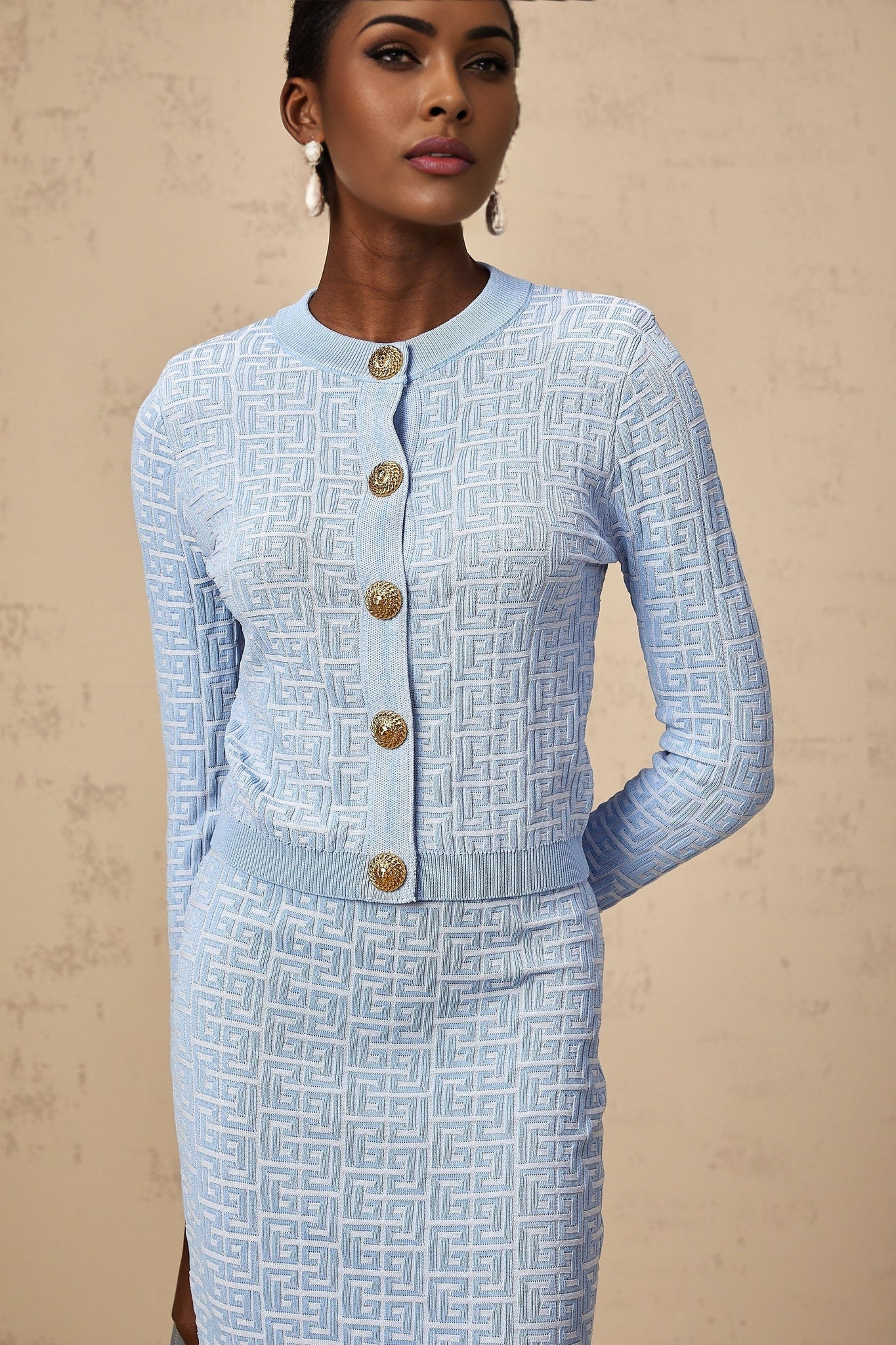 Woman wearing a matching knit cardigan and skirt set with patterned jacquard design in soft pastel colors