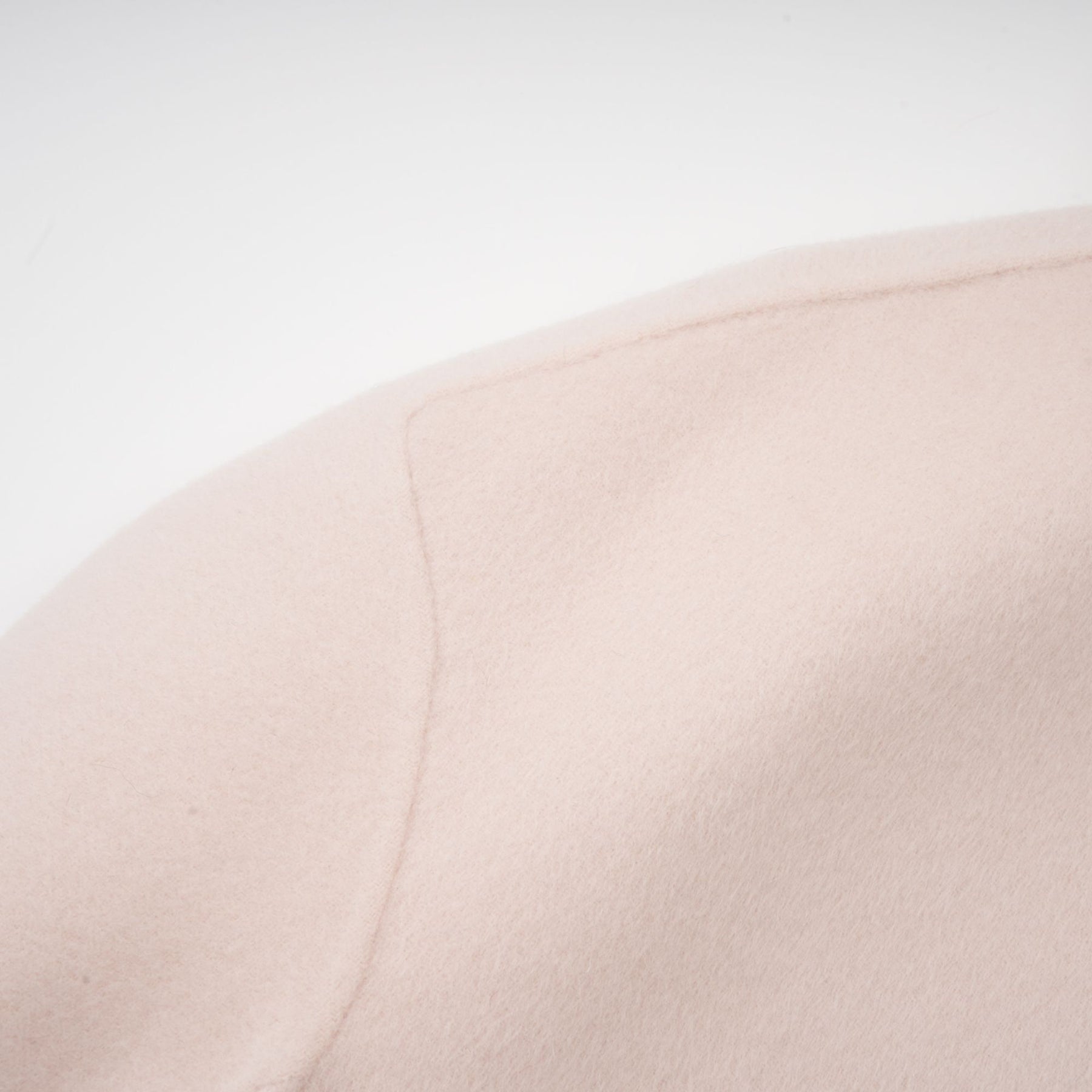 A short pink coat with a diagonal placket closure worn by a model against a plain background