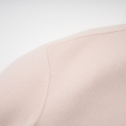 A short pink coat with a diagonal placket closure worn by a model against a plain background