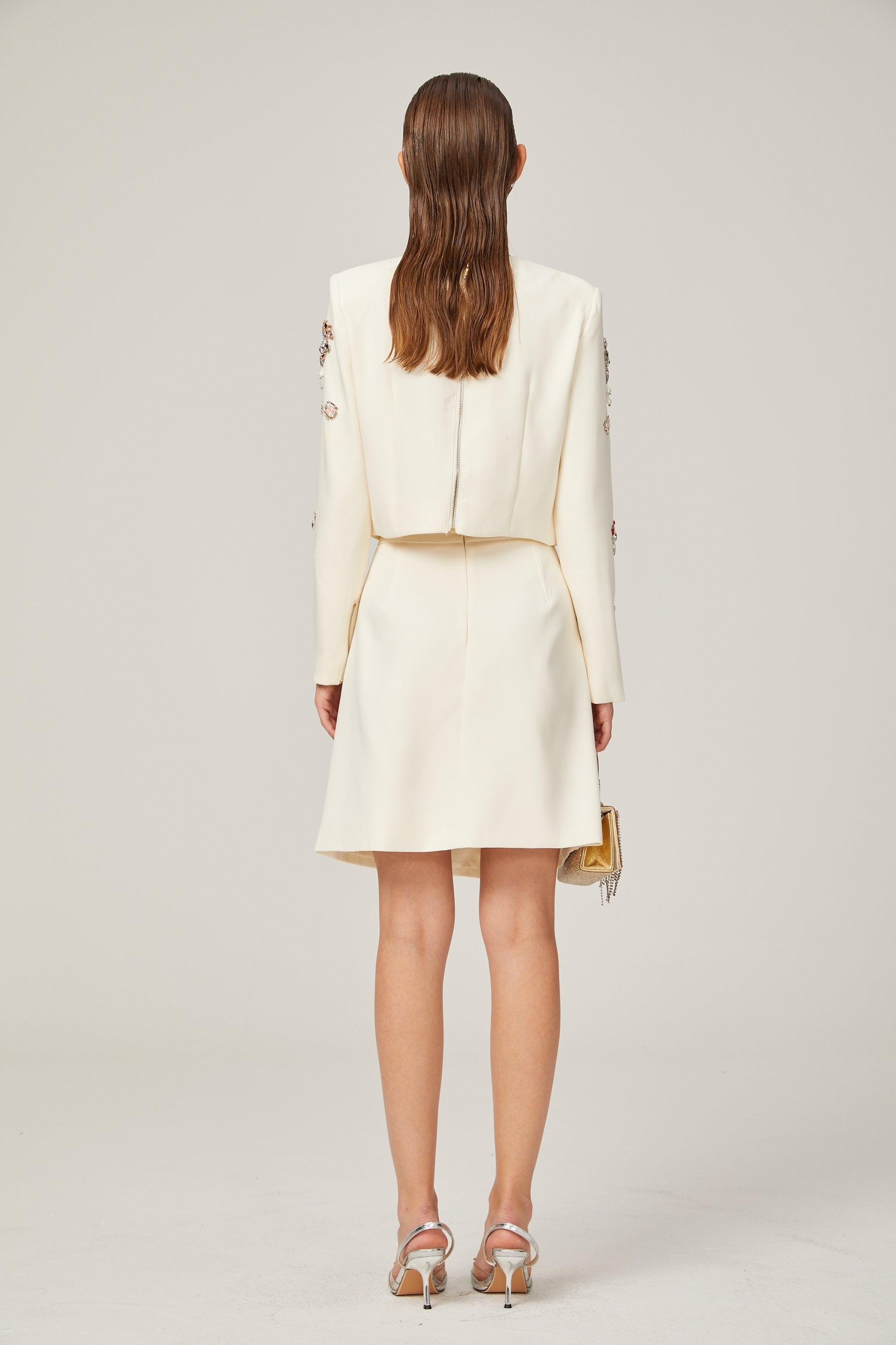 Woman wearing white twopiece outfit with crystal embellishments top and skirt set named Jeanne
