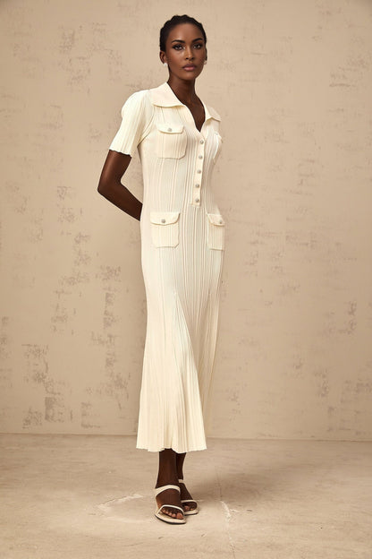 A woman wearing a formfitting ribbed knit midi dress in a neutral color standing in a relaxed pose
