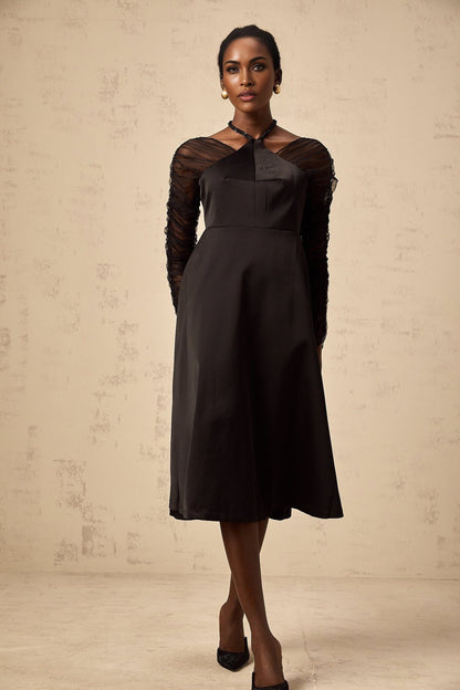 Woman wearing a black halterneck midi dress with panelled design standing in a neutral pose