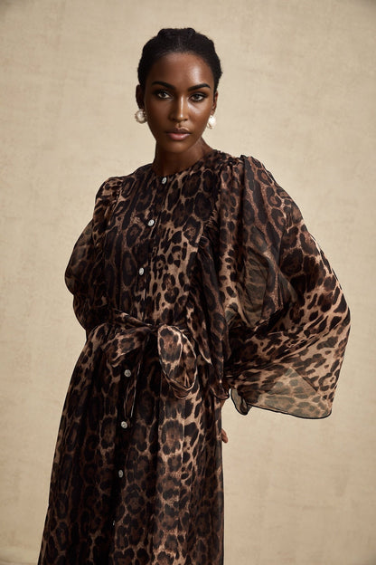 A woman wearing a leopard print midi dress with a single breasted design and long sleeves