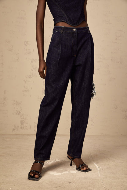 A pair of blue high rise jeans with pleated details on the front featuring a relaxed fit and a light wash denim fabric