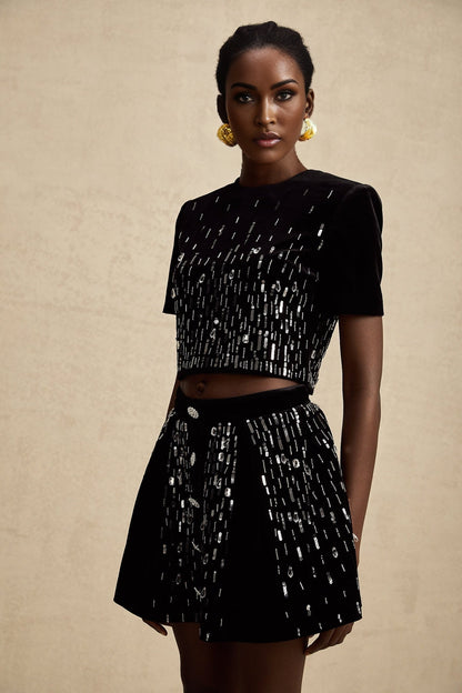 A black velvet two piece outfit consisting of a top and skirt set with embellishments called Isabeau The top and skirt are matching and feature decorative details on the fabric