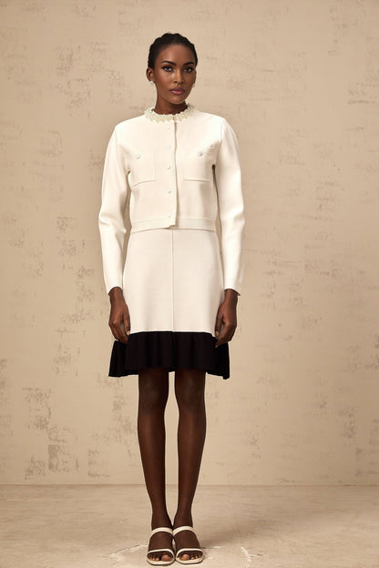 A white knitted cardigan adorned with faux pearl embellishments featuring a classic button front design