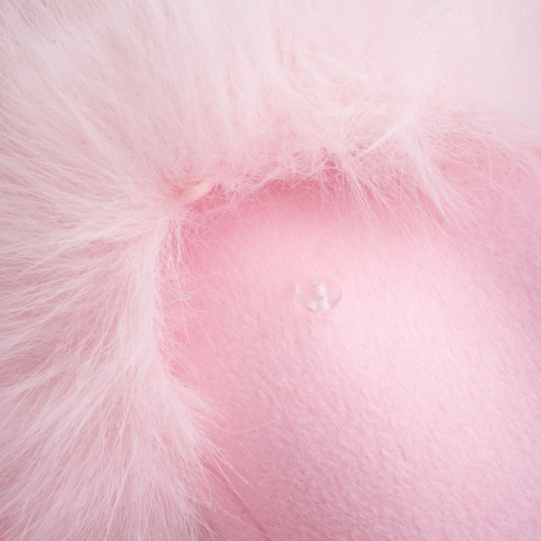 A pink oversized coat made of faux fur with a plush texture and long sleeves