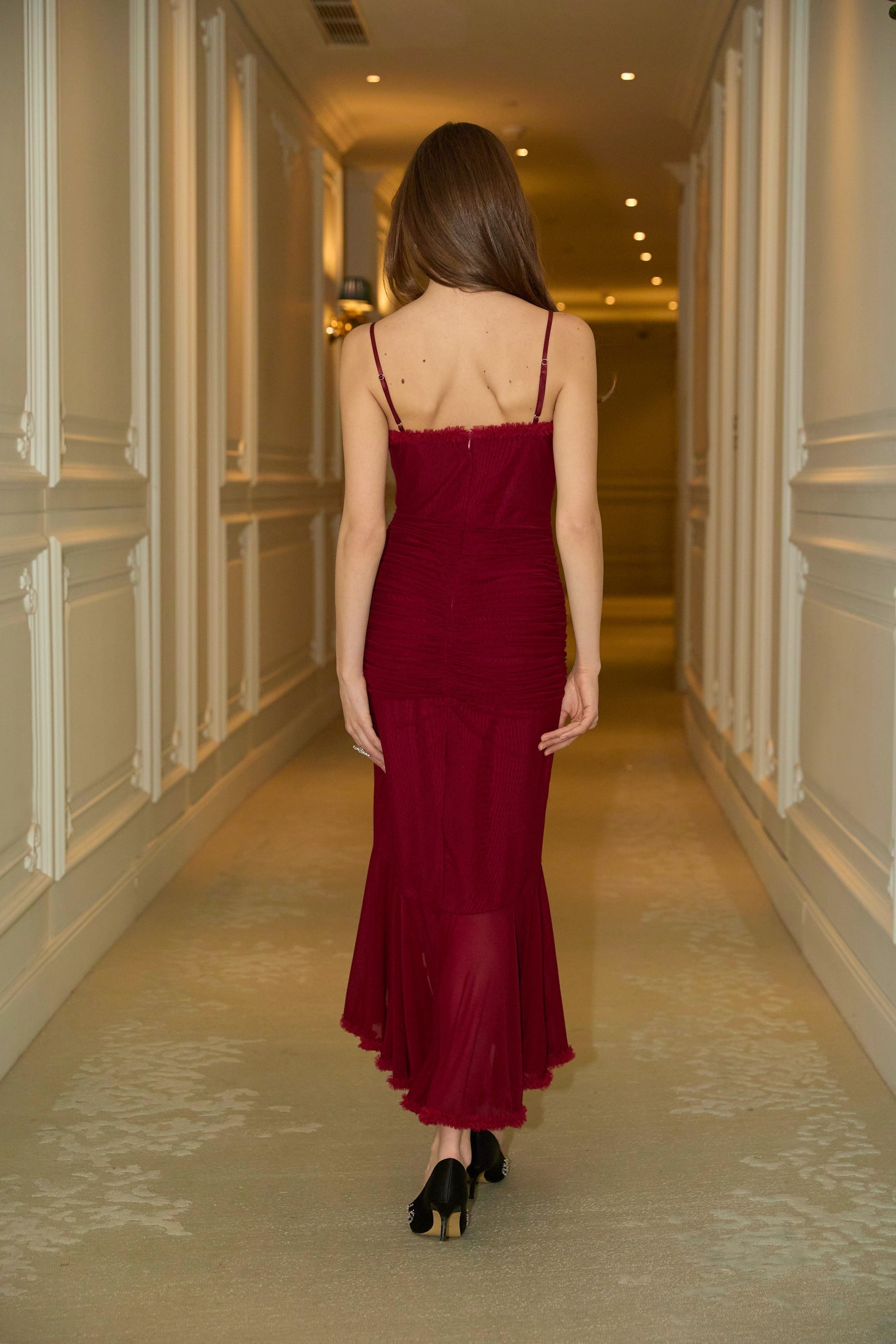 A red maxi dress with ruffle details and draped fabric featuring a long flowing skirt and feminine silhouette
