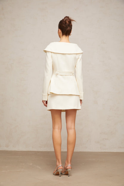 A white peplum jacket paired with a matching skirt creating an elegant two piece ensemble
